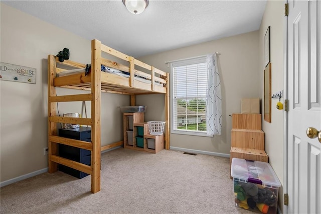 bedroom with carpet, baseboards, and a textured ceiling