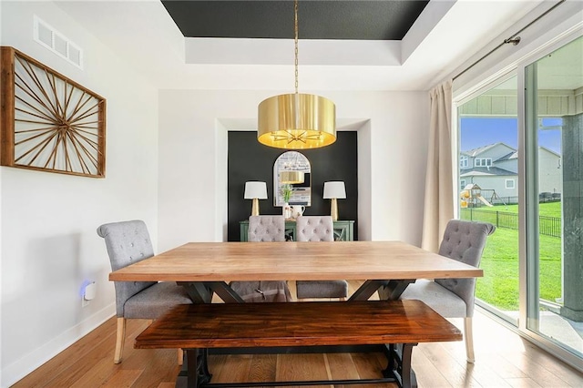 1309 NW 107th Ter, Kansas City, MO 64155 - dining room featuring wood finished floors, a raised ceiling, and baseboards