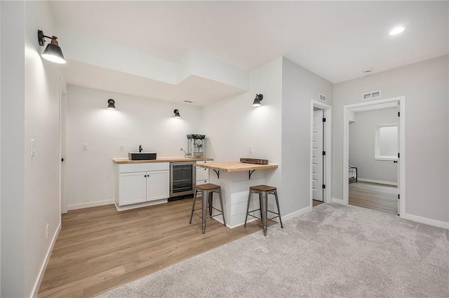 1309 NW 107th Ter, Kansas City, MO 64155 - kitchen featuring wine cooler, wood counters, a kitchen breakfast bar, white cabinetry, and baseboards