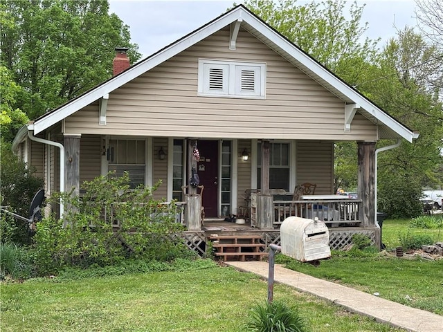 12418 3rd St, Grandview, MO 64040 - view of front facade with covered porch, a chimney, and a front lawn