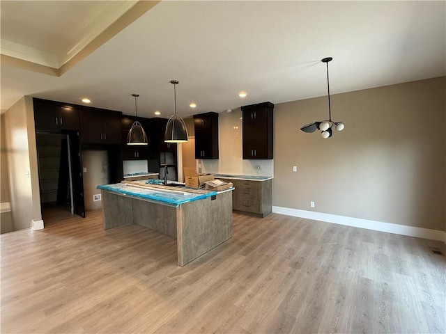 202 E Maple St, Lone Jack, MO 64070 - kitchen featuring a center island, light wood-style flooring, recessed lighting, dark cabinets, and pendant lighting