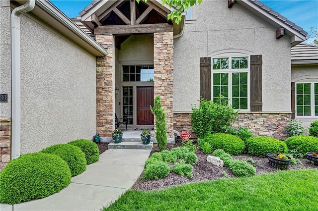 view of exterior entry featuring stone siding and stucco siding