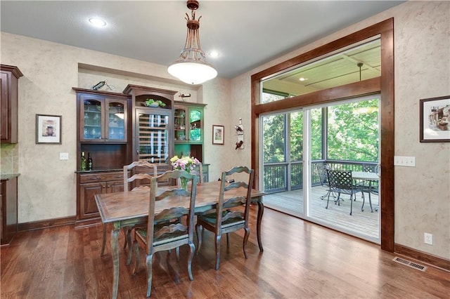 dining space featuring dark wood finished floors, baseboards, and a textured wall