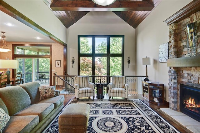 living room featuring high vaulted ceiling, a fireplace, beam ceiling, wood finished floors, and wooden ceiling
