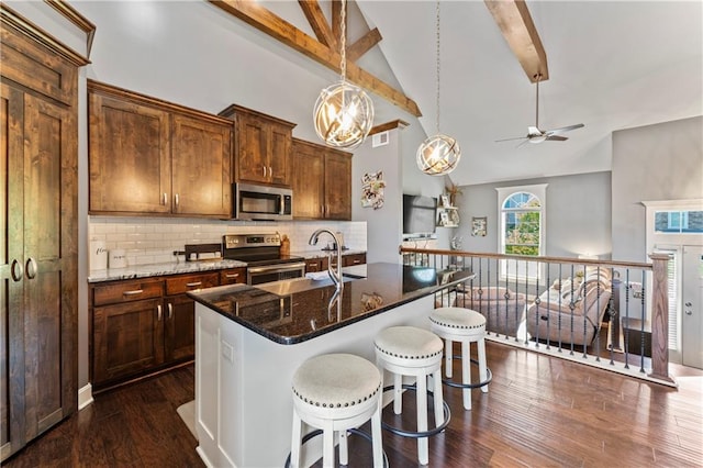 31560 W 85th St, De Soto, KS 66018 - kitchen with appliances with stainless steel finishes, ceiling fan, beam ceiling, decorative backsplash, and a breakfast bar area