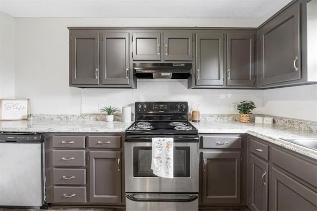 kitchen with under cabinet range hood, stainless steel appliances, backsplash, and light stone countertops