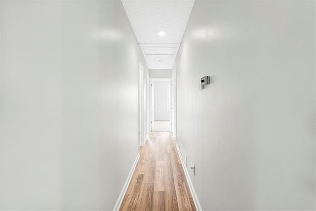 hall featuring light wood finished floors, baseboards, and recessed lighting