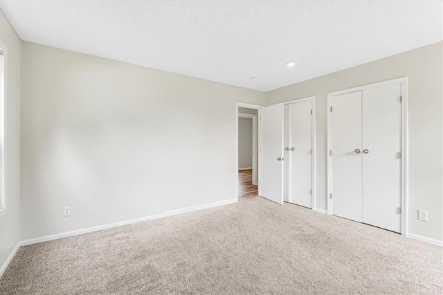 unfurnished bedroom with carpet flooring, multiple closets, baseboards, and recessed lighting