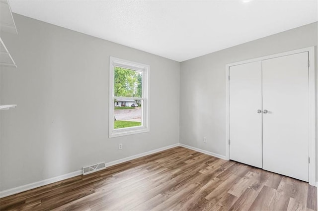 unfurnished bedroom with wood finished floors, baseboards, and a closet