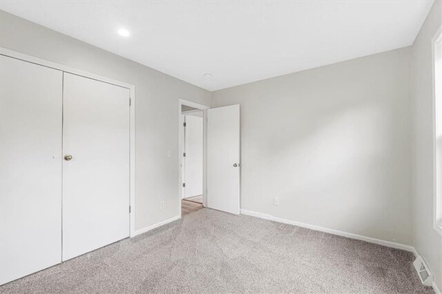 unfurnished bedroom featuring carpet flooring, baseboards, recessed lighting, and a closet