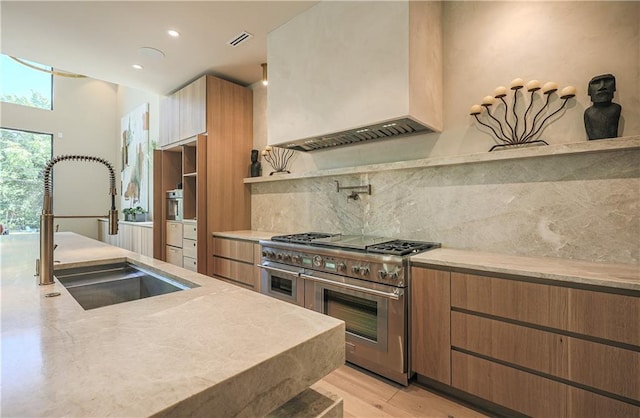 kitchen with range with two ovens, a sink, healthy amount of natural light, backsplash, and recessed lighting