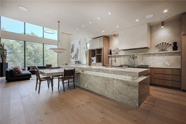 kitchen with modern cabinets, a sink, light wood-style flooring, tasteful backsplash, and recessed lighting