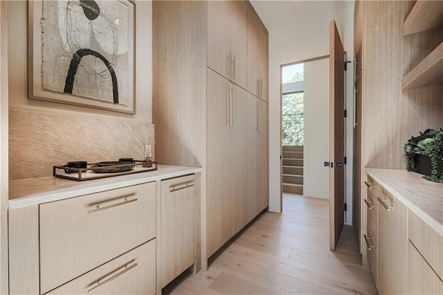 kitchen with backsplash, light countertops, light wood-type flooring, and open shelves