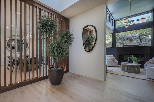 foyer featuring wood finished floors, a glass covered fireplace, a towering ceiling, and a chandelier