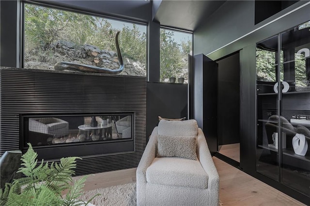 sitting room with a glass covered fireplace and wood finished floors