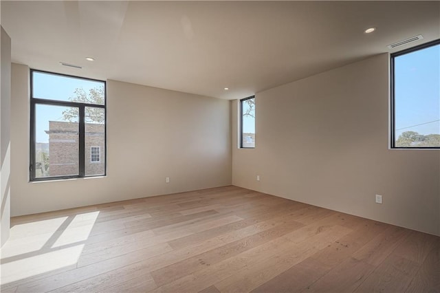empty room with light wood-style flooring, recessed lighting, and floor to ceiling windows