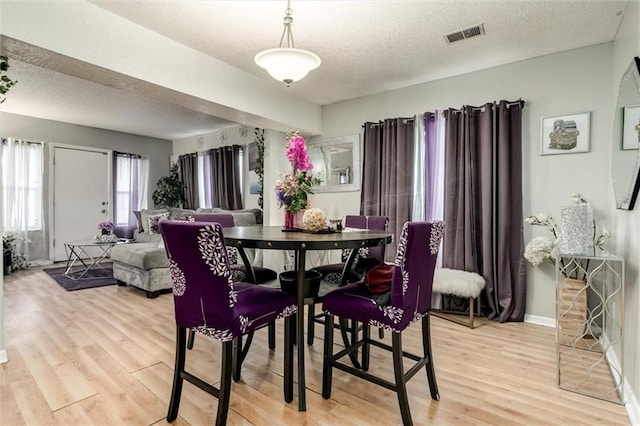 2713-2715 Benton Blvd, Kansas City, MO 64128 - dining room featuring light wood-style floors, a textured ceiling, and baseboards