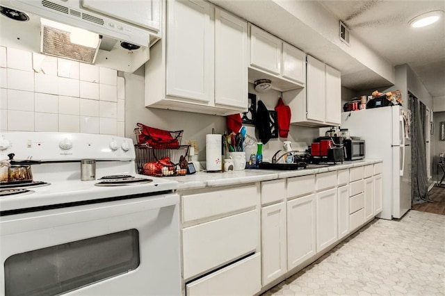 2713-2715 Benton Blvd, Kansas City, MO 64128 - kitchen featuring white appliances, under cabinet range hood, light countertops, white cabinetry, and recessed lighting