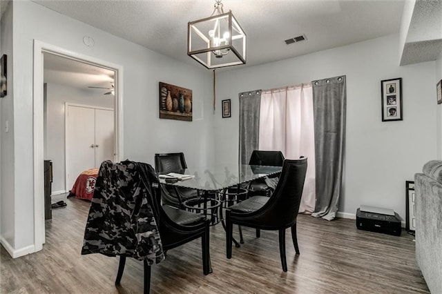 2713-2715 Benton Blvd, Kansas City, MO 64128 - dining room with wood finished floors, baseboards, a chandelier, and a textured ceiling