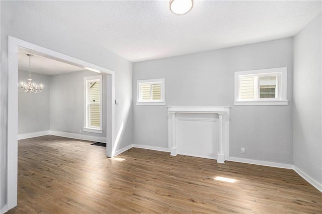 2206 E 30th St, Kansas City, MO 64109 - spare room with a chandelier, wood finished floors, and a textured ceiling
