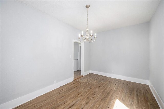 2206 E 30th St, Kansas City, MO 64109 - spare room featuring a chandelier and wood finished floors