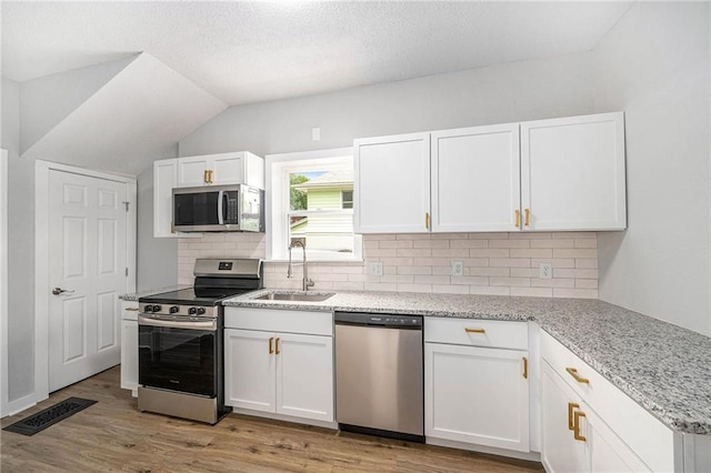 2206 E 30th St, Kansas City, MO 64109 - kitchen with stainless steel appliances, tasteful backsplash, white cabinets, light wood-style floors, and light stone counters