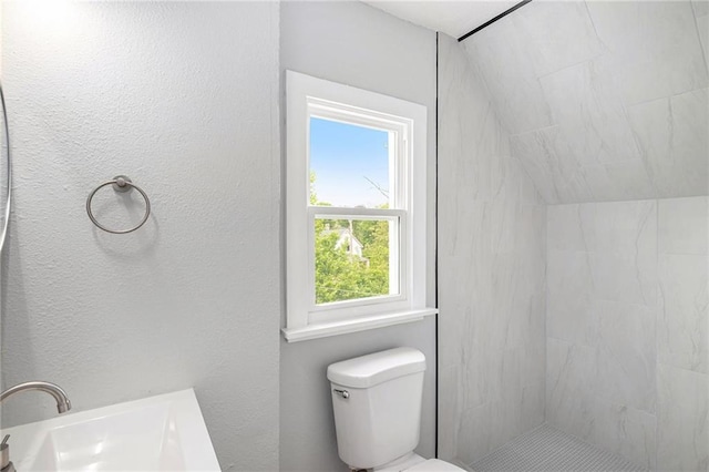 2206 E 30th St, Kansas City, MO 64109 - bathroom with tiled shower, lofted ceiling, and a textured wall