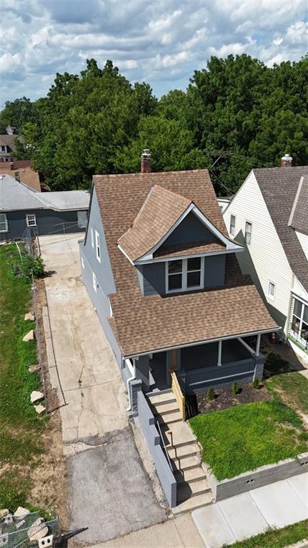 2206 E 30th St, Kansas City, MO 64109 - view of front facade with roof with shingles, covered porch, a chimney, and a front yard