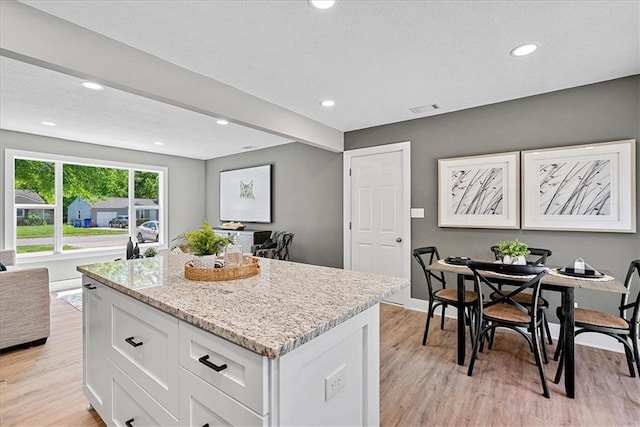 11424 W 68th Pl, Shawnee, KS 66203 - kitchen with open floor plan, light wood-style flooring, a center island, light stone counters, and white cabinets