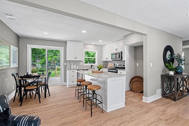 11424 W 68th Pl, Shawnee, KS 66203 - kitchen featuring stainless steel appliances, light wood-style flooring, a breakfast bar, a textured ceiling, and recessed lighting