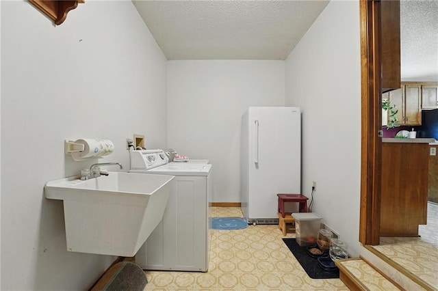 washroom with a textured ceiling, washer and dryer, and light floors