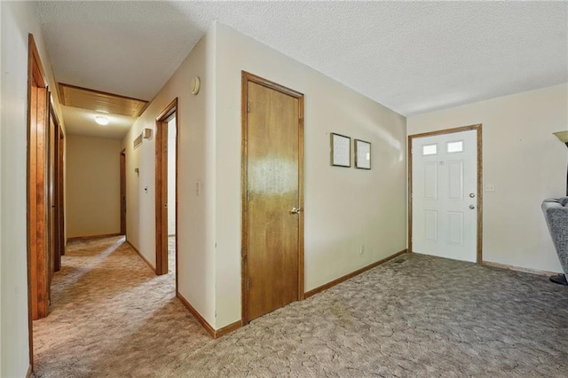 entryway with carpet flooring, a textured ceiling, and baseboards