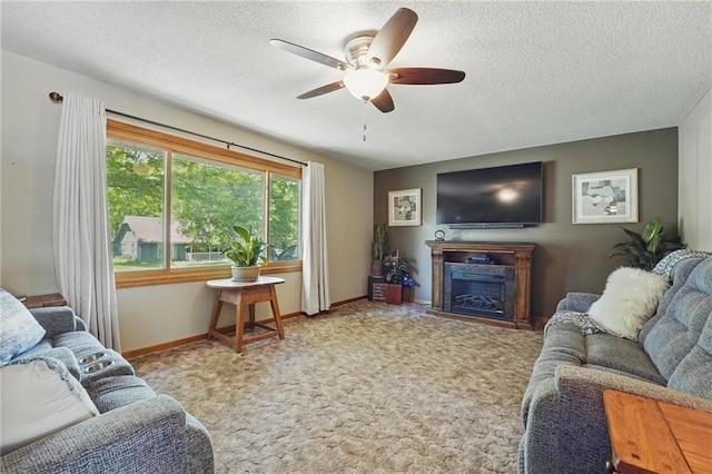 living room featuring ceiling fan, a textured ceiling, a fireplace, carpet floors, and baseboards