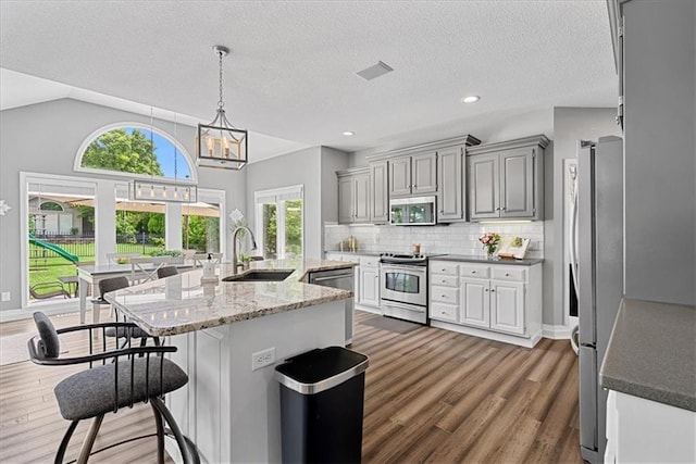 19600 W 98th St, Lenexa, KS 66220 - kitchen featuring appliances with stainless steel finishes, a sink, dark wood finished floors, decorative backsplash, and a breakfast bar area