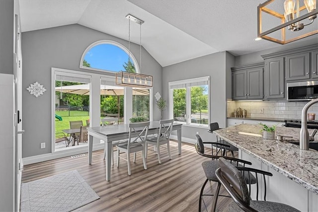 19600 W 98th St, Lenexa, KS 66220 - dining space featuring vaulted ceiling, wood finished floors, baseboards, and a chandelier
