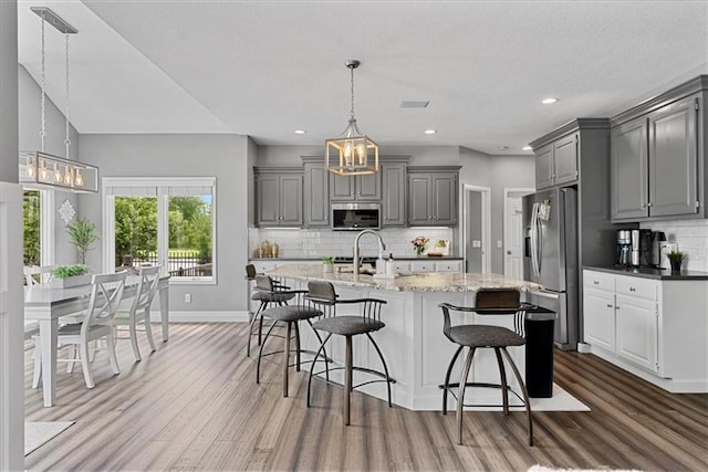 19600 W 98th St, Lenexa, KS 66220 - kitchen with appliances with stainless steel finishes, gray cabinetry, wood finished floors, a chandelier, and recessed lighting