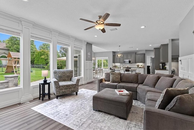 19600 W 98th St, Lenexa, KS 66220 - living area featuring a decorative wall, ceiling fan, light wood finished floors, recessed lighting, and a textured ceiling