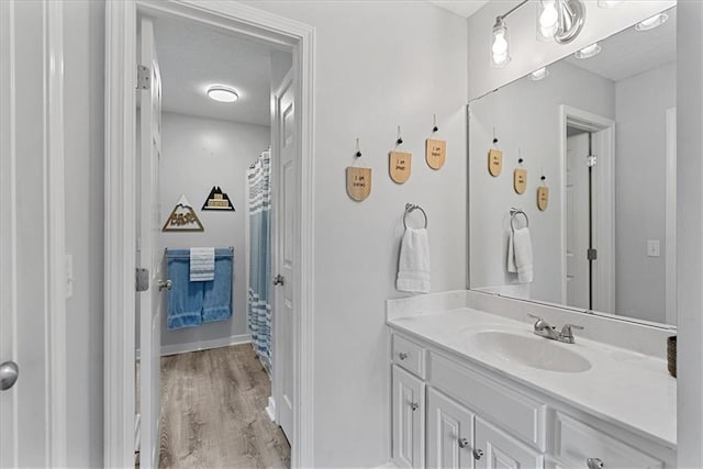 19600 W 98th St, Lenexa, KS 66220 - full bathroom featuring vanity, wood finished floors, a shower with shower curtain, a textured ceiling, and baseboards
