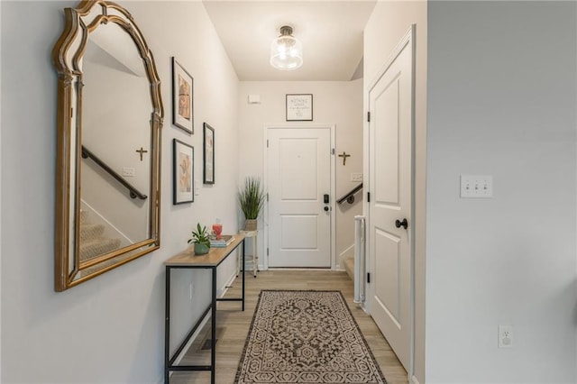 doorway with light wood-style flooring and baseboards
