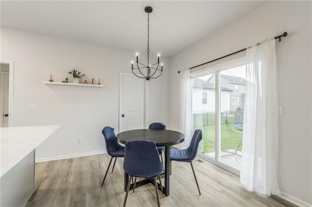 dining area featuring healthy amount of natural light, light wood-style floors, a chandelier, and baseboards
