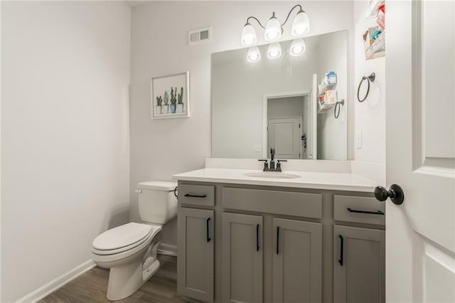 bathroom featuring toilet, baseboards, wood finished floors, and vanity