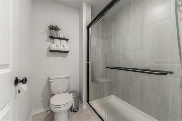 full bathroom with toilet, a stall shower, and baseboards