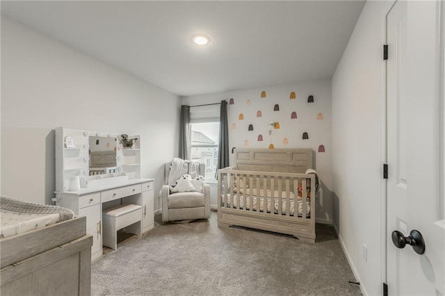 bedroom featuring light colored carpet, a nursery area, and baseboards