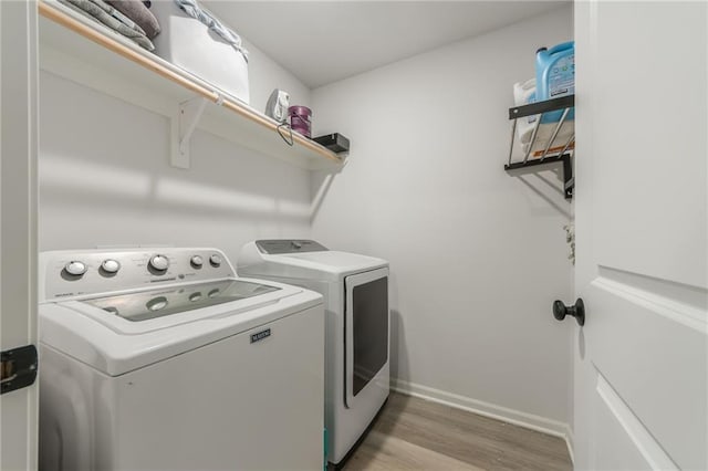 laundry area featuring washer and dryer, light wood-style flooring, and baseboards