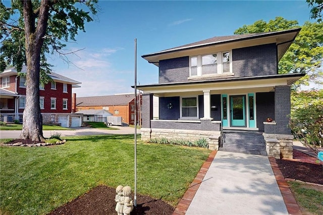 american foursquare style home featuring brick siding, a porch, and a front yard