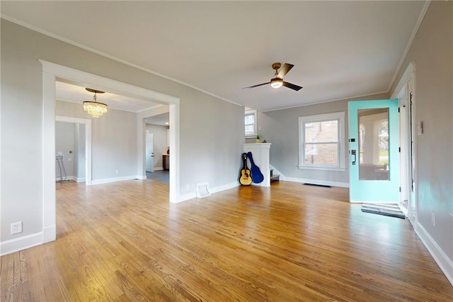 unfurnished living room with ornamental molding, light wood-style floors, baseboards, a chandelier, and a ceiling fan