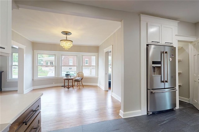 kitchen featuring stainless steel fridge, white cabinetry, a chandelier, ornamental molding, and dark wood finished floors