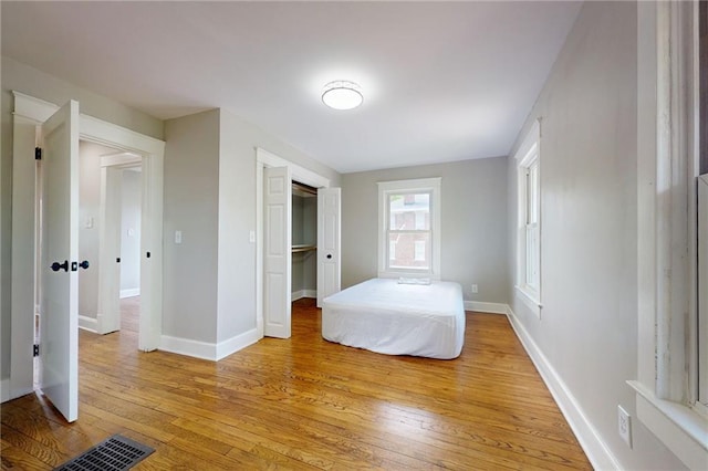 unfurnished bedroom with light wood-type flooring, baseboards, and a closet