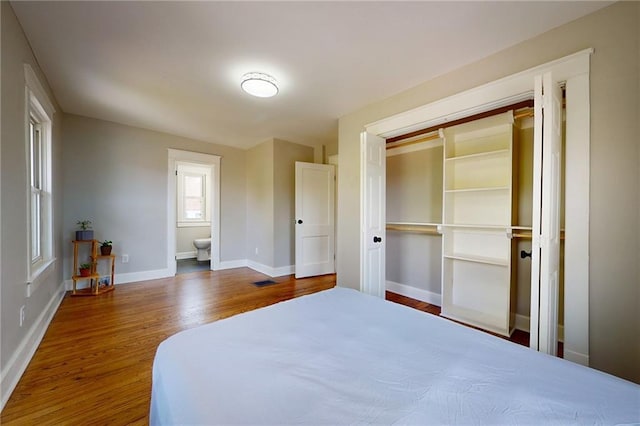 bedroom with wood finished floors, baseboards, and a closet