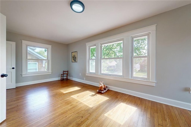 empty room with healthy amount of natural light, baseboards, and hardwood / wood-style floors